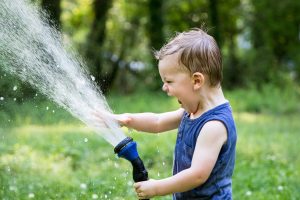 Child playing in outdoor hose spray